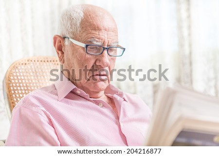 old man reading a newspaper at home
