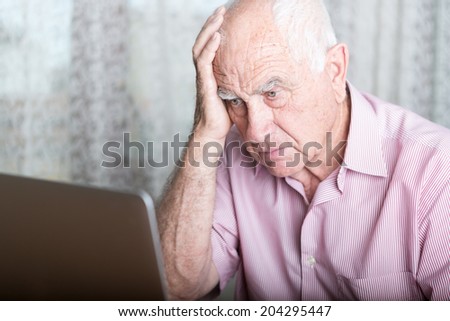 technology, oldness and lifestyle concept - old man in working with laptop computer at home concerned