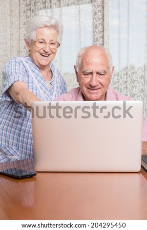 Happy smiling retired couple using computer laptop at home