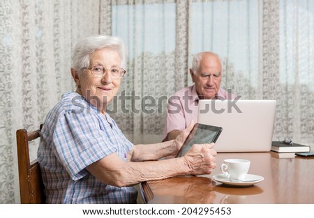 Happy smiling retired couple using computer laptop at home