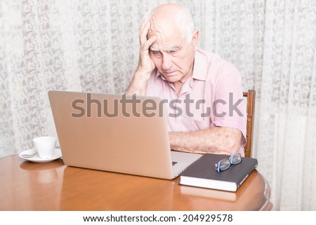 technology, oldness and lifestyle concept - old man in working with laptop computer at home concerned