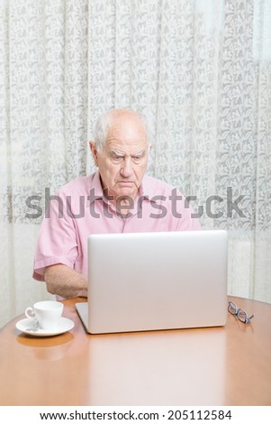 Serious mature man using laptop at table