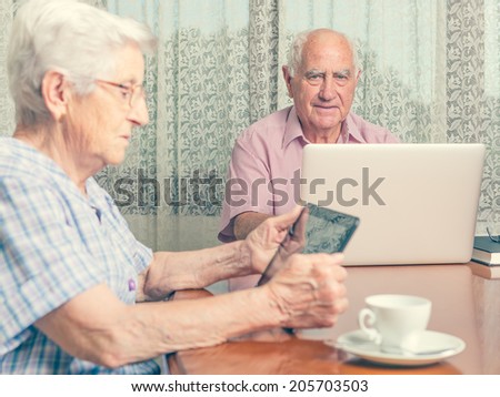 Happy senior couple surfing the internet with laptop computer and tablet