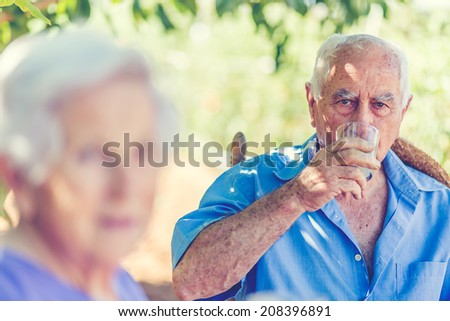 Aged couple is sitting under a tree in garden