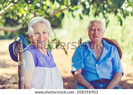 Aged couple is sitting under a tree in garden