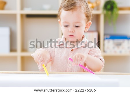 Cute little boy playing with pen and pencils at the nursery school