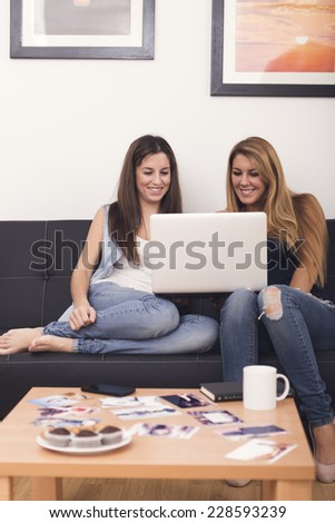 two women using laptop on sofa in her home