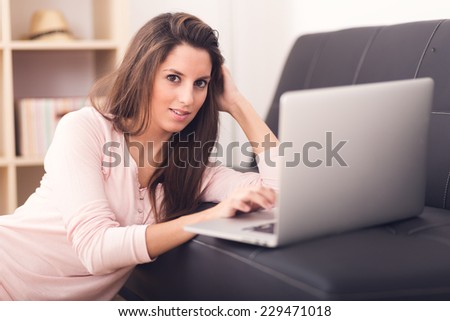 Smiling young woman looking on your laptop sitting on floor at home
