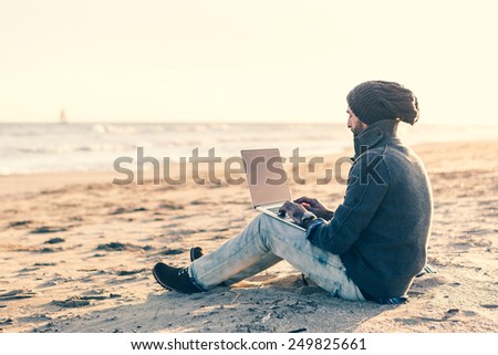 Man work on computer at the beach at sunset