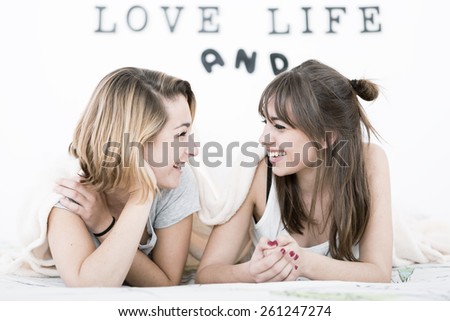 Beautiful young women smiling under white bed sheets.