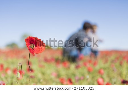 Mother and her little child having fun in a field, flower in foreground