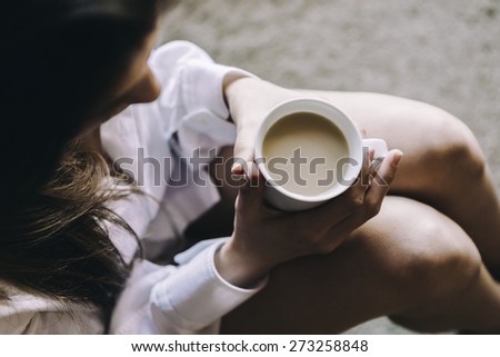 woman floor with cup of coffee in hands, top view point