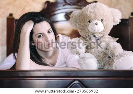 Happy woman lying in bed with her teddy bear at home