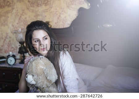 happy woman sitting on bed with a teddy bear at home