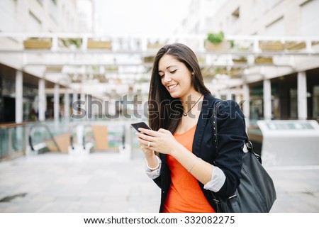 Portrait of a beautiful young businesswoman standing outside using mobile phone