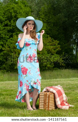 Beautiful young woman on picnic speaking by phone