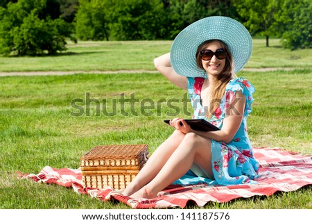 Beautiful young woman on picnic working on tablet