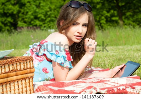 Beautiful young woman on picnic working on tablet