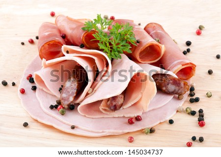 cooked ham, smoked ham and dried pork sausage served on wood with spices
