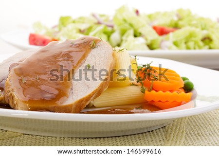 Roasted pork shoulder served with pasta and vegetables