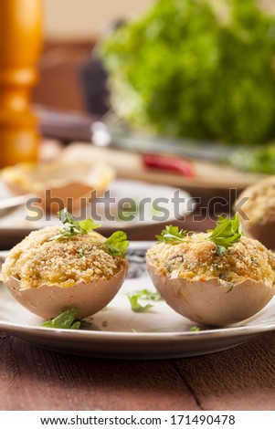 Baked eggs, stuffed with ham and parsley, served in the eggshell - focus on egg