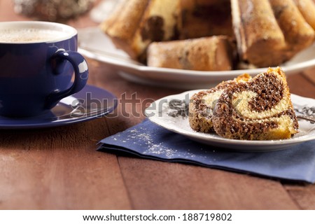 marble ring cake with a castor sugar and a cap of coffee - focus on a piece of cake