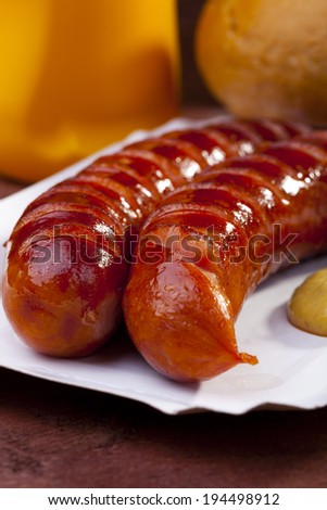 Roasted sausage with bread served on a paper tray - wood board