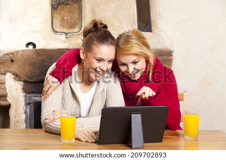 Two beautiful women work on the tablet during the holidays