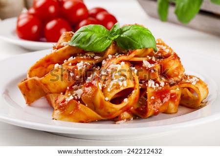 Pasta tagiatelle with tomato on white woodboard