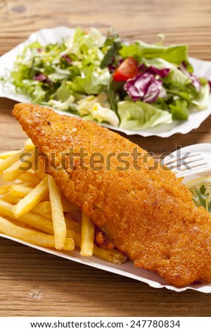 Fried fish and chips on a paper tray - Natural wooden background