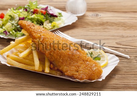 Fried fish and chips on a paper tray - Natural wooden background
