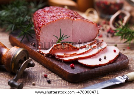 Delicious smoked ham on a wooden board with spices.