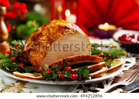 Christmas baked ham, served on the old plate. Spruce twigs all around. Front view.