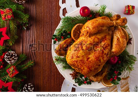 Roasted whole chicken with Christmas decoration. Wooden background. Top view.