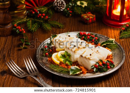 Christmas fish. Roasted cod pieces, served in vegetable sauce. Xmas styling. Front view.