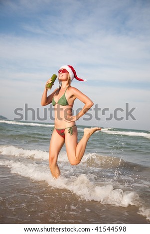 Happy beautiful woman in christmas hat dancing on the beachfront