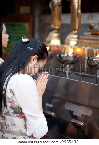 CHIANG MAI, THAILAND - FEBRUARY 4: Buddhist woman praying on evening religion ceremony in Doi Suthep Wat on February 4, 2012 in Chiang Mai, Thailand