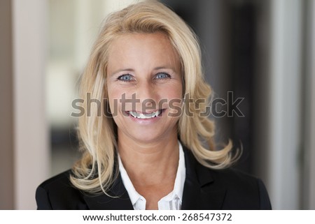 Mature woman smiling at the camera. She is successful and got a lot of leadership.