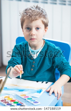 Little boy drawing with watercolor paints