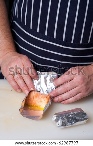 Chef wrapping up salmon rolls in aluminum foil