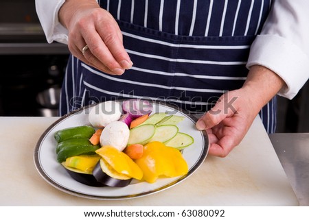 Chef seasons vegetables with salt
