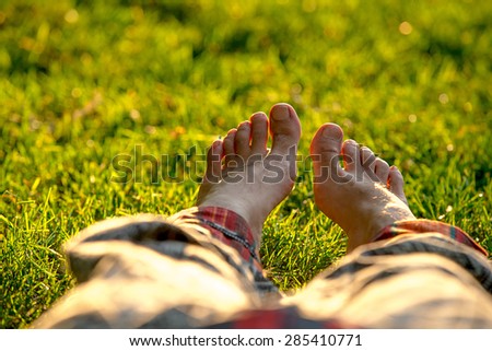 Male feet on the grass closeup with beautifl bokeh at background