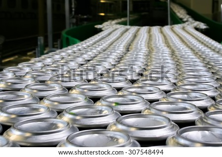 Conveyor line carrying thousands aluminum beverage cans at factory. Concept of industrial growth.