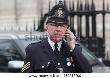 LONDON - APRIL 17: An policeman talks on his phone outside of the funeral service for Margaret Thatcher at St. Paul\'s Cathedral on April 17, 2013 in London.