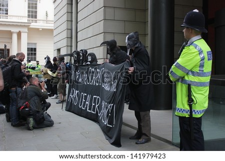 LONDON - June 12: A Police officer watches as demonstrators chant anti-arms slogans in Carlton Gardens on June 12, 2013 in London.