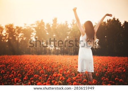 Young girl on poppy field hands up