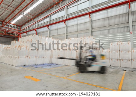 worker driving a forklift loader in warehouse with load jumbo bag