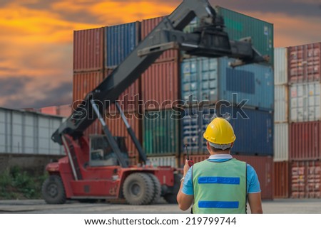 Foreman control forklift handling the container box load to big truck selective focust at container box.