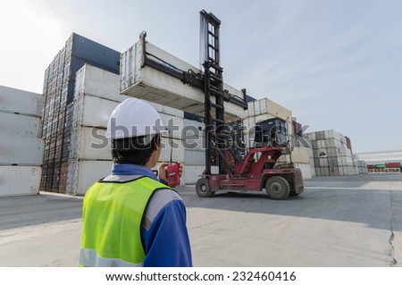 foreman control forklift handling the container box load to big truck selective focus at container box.