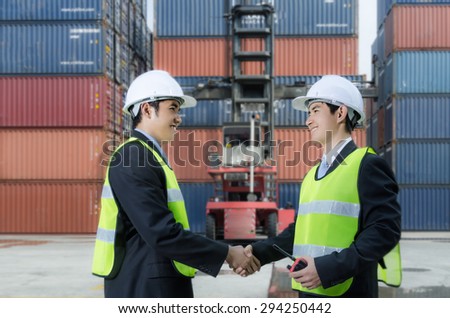Two business man handshaking before stack of containers